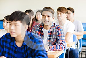 Smiling asian male college student sitting with classmates