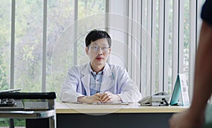 Smiling Asian male pediatrician give advice to patients , Young asia male doctor consult female patient and checkup in hospital ,