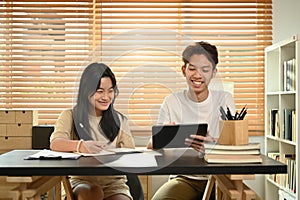 Smiling asian male private tutor helping young student with homework. Tutorial and educational concept