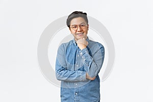 Smiling asian male student, freelancer in blue shirt and glasses listening with interest, nod while having conversation