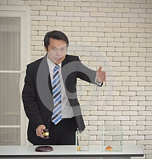 Smiling asian man in black suit with wooden gavel in hand wait people bidding auction concept