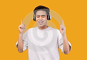 Smiling asian man enjoying music with headphones