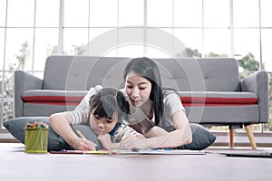 Smiling Asian mother and little asian girl child is drawing and Painting with wooden colored pencils on paper for imagination