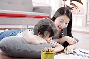 Smiling Asian mother and little asian girl child is drawing and Painting with wooden colored pencils on paper for imagination