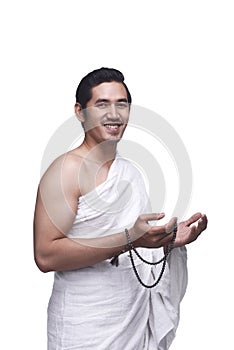 Smiling asian muslim man wearing ihram clothes with prayer beads