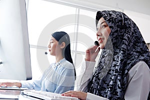 Smiling asian Muslim women is call center or secretary operator is wearing a headset and a microphone for consultant to customers