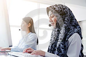 Smiling asian Muslim women is call center or secretary operator is wearing a headset and a microphone for consultant to customers