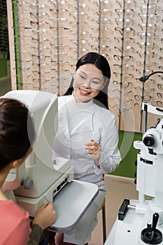 smiling asian oculist testing vision of
