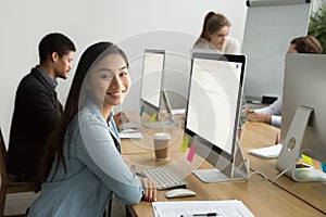 Smiling asian office employee looking at camera working with col