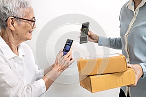 Smiling asian senior grandmother scanning QR code pay for service to delivery employee,contactless transactions,cashless society,