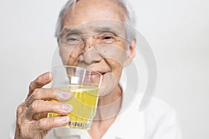 Smiling asian senior woman is drinking a glass of vitamin C,orange juice,old elderly with effervescent vitamin C,strengthening the