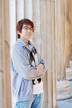 Smiling asian student holding books outdoors