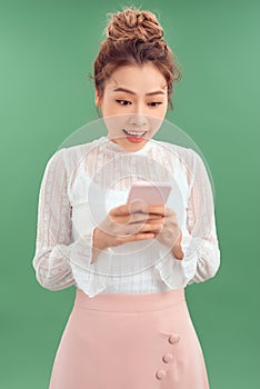 Smiling Asian woman in business clohes and typing on her smartphone ove background