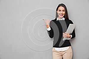 Smiling asian woman in business clothes holding laptop computer