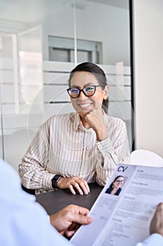 Smiling Asian woman candidate and hr manager holding cv during job interview.