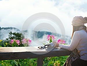 Smiling asian Woman drinking coffee and tea and take a photo and relax in sun sitting outdoor in sunshine light enjoy relax her wa