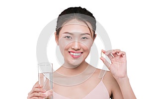 Smiling asian woman eating pills and drinking water