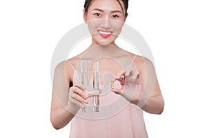 Smiling asian woman eating pills and drinking water