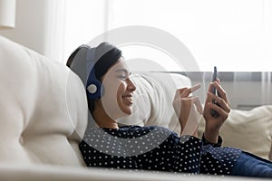 Smiling asian woman in headphones using smartphone at home