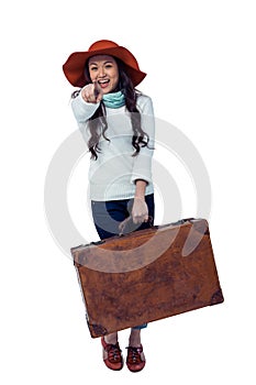 Smiling Asian woman holding luggage pointing the camera