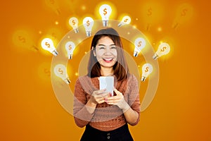 smiling Asian woman holding mobile phone with lightbulb icon and dollar sign  idea for make money online  e-business concept