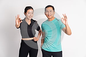 smiling asian woman and man standing with ok hand gesture