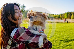 Smiling Asian Woman Petting Dog Outdoors In Grass