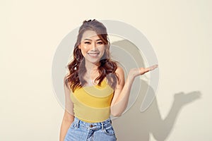 Smiling asian woman showing open hand palm to to the copy space for product or something