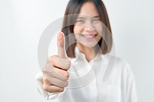 Smiling Asian woman and showing thumbs up or like on gray background.