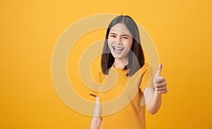 Smiling Asian woman and showing thumbs up or like on yellow background.