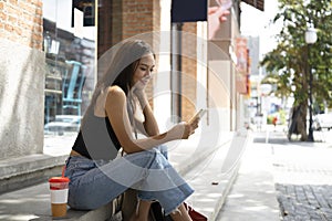 Asian woman sitting on stairs using smart phone.