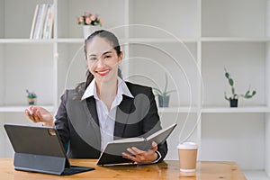 Smiling asian woman sitting and using digital tablet at cafe browsing Internet or shopping, happy satisfied young female