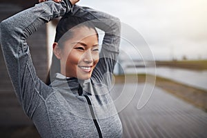 Smiling Asian woman in sportswear stretching before exercising o