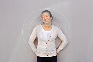 Smiling asian woman standing against gray wall