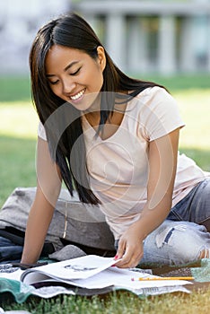 Smiling asian woman student studying outdoors. Looking aside.