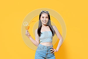 Smiling Asian woman in summer outfit with a glass of orange juice