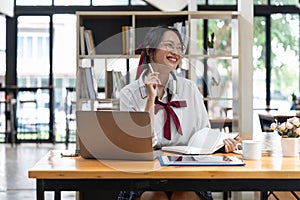 Smiling asian woman takes notes watching webinars on the laptop,researching business tasks, a male student is studying