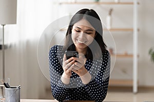 Smiling asian woman use modern cellphone at home