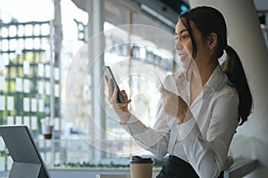 Smiling asian woman using mobile phone and holding credit card for online payment or online shopping.