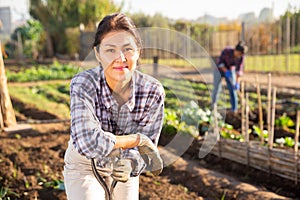 Smiling asian woman in vegetable garden on sunny day