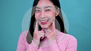 Smiling Asian woman wearing orthodontic retainer on blue screen background. Dental care and teeth