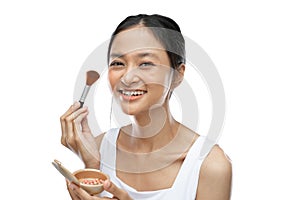 smiling asian woman wearing underdress applying make up with brush