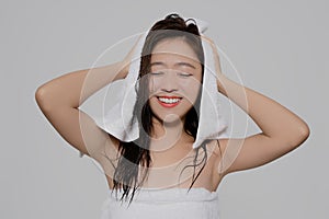 Smiling Asian woman is wiping her hair dry after taking a shower