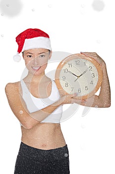 Smiling asian women in a Santa`s hat with a clock