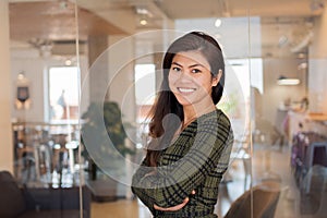 Smiling Asian worker with arms crossed in office