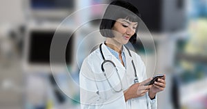 Smiling asian young female doctor using smart phone while standing in hospital