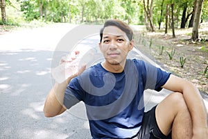 Smiling Asian young man in navy blue sportwear Thirsty and drinking water in bottle after exercise and running in garden