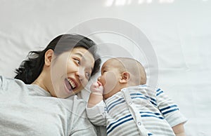 Smiling Asian Young mother with her little cute baby son playing lying on bed together, Happy mother`s day