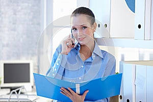 Smiling assistant on phone call holding folder