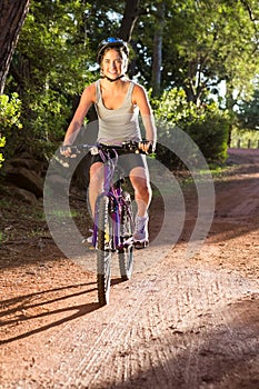 Smiling athletic brunette mountain biking on path